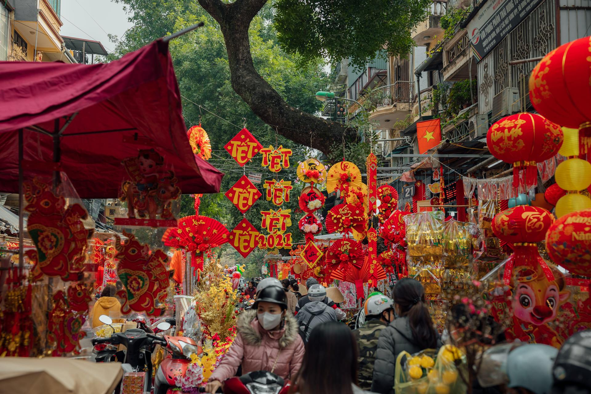 Vibrant Vietnamese street market filled with festive red and gold decorations, lanterns, and shoppers celebrating the Lunar New Year, Tết.