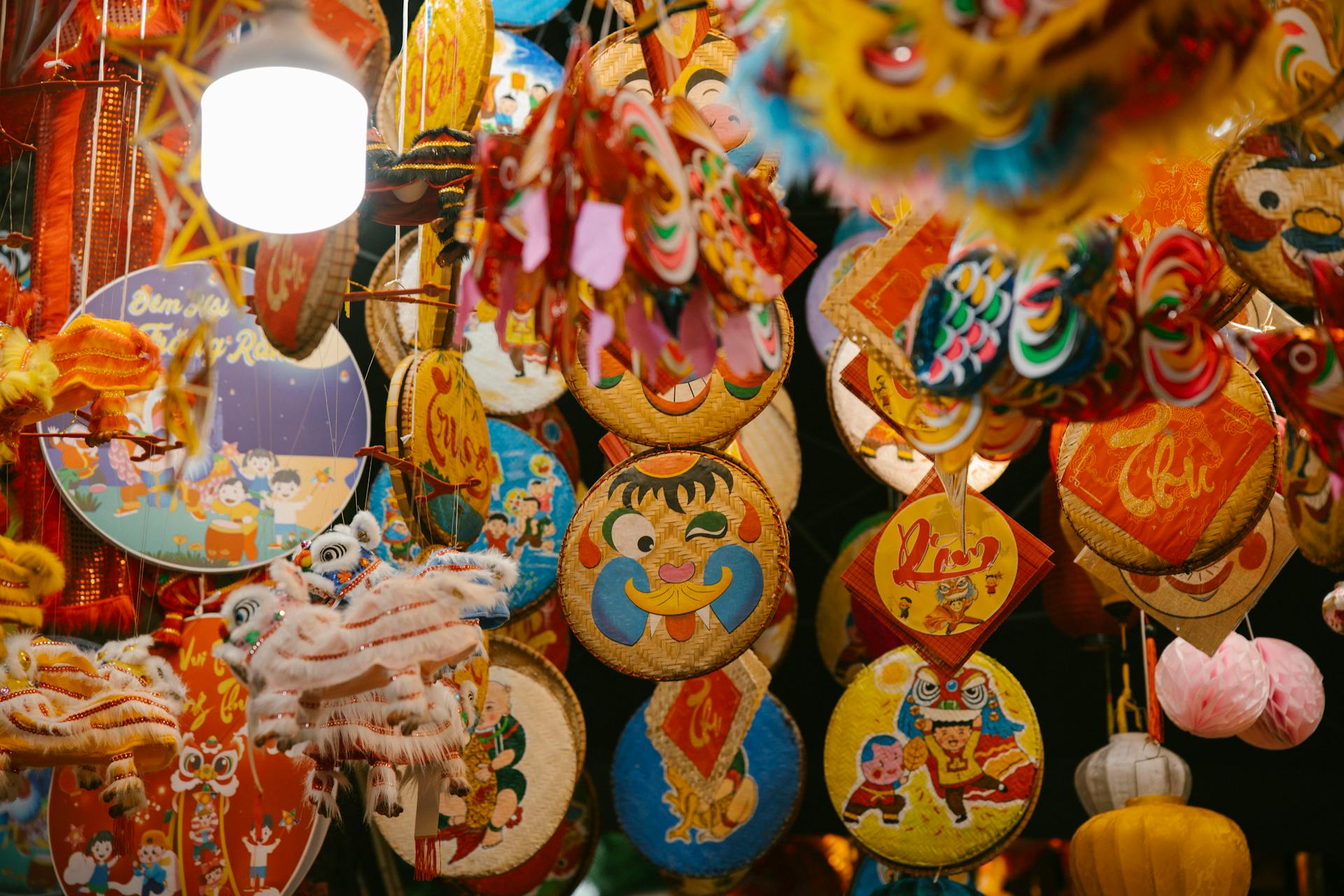 Vibrant Mid-Autumn Festival stall in Vietnam featuring colorful paper lanterns and woven bamboo discs painted with festive folk characters.