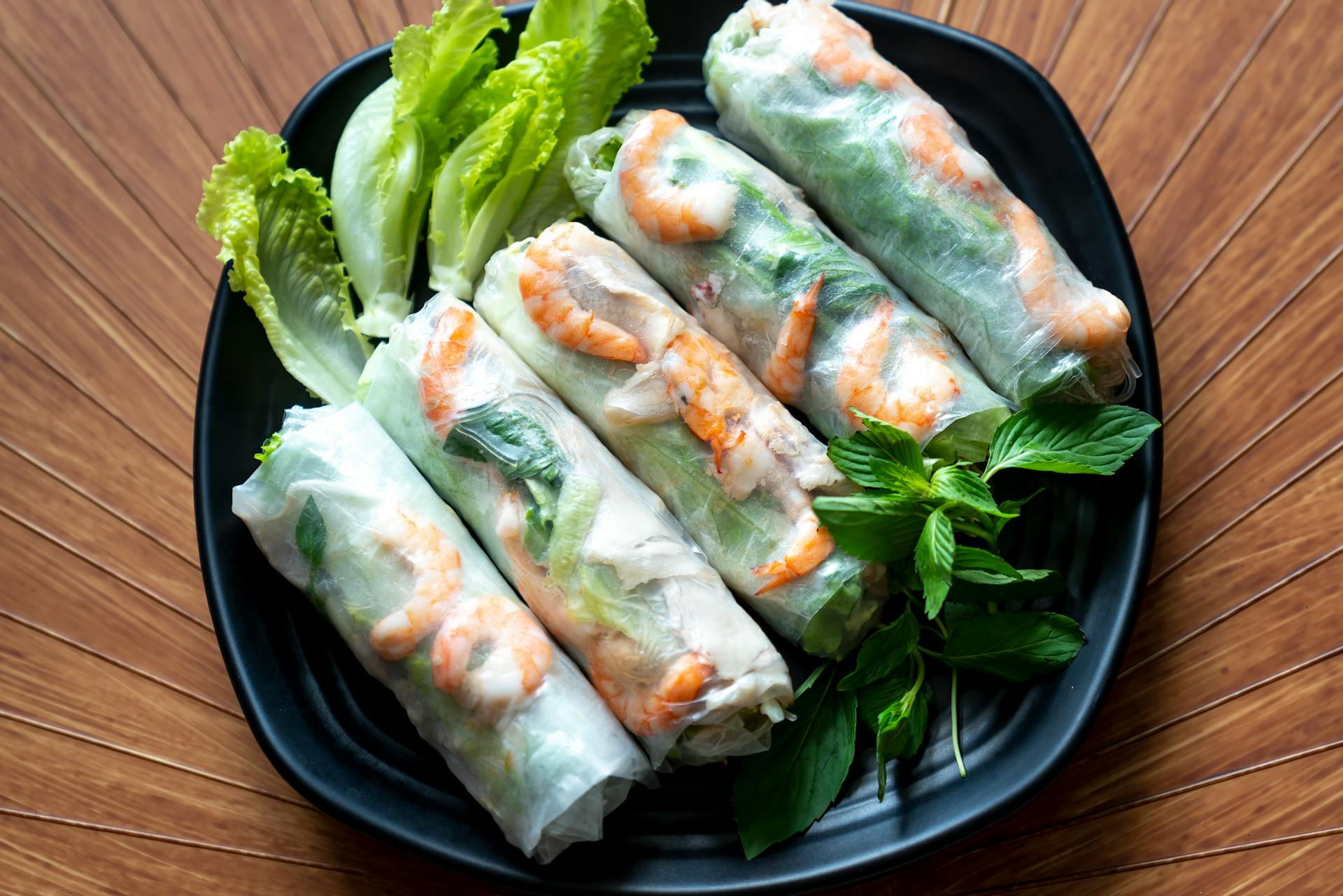 Fresh Vietnamese spring rolls (Gỏi cuốn) featuring translucent rice paper, bright orange shrimp, pork, and vibrant green herbs.
